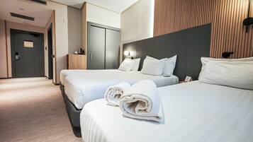 Une chambre d’hôtel avec deux lits, un mur décoratif en bois et un minibar.