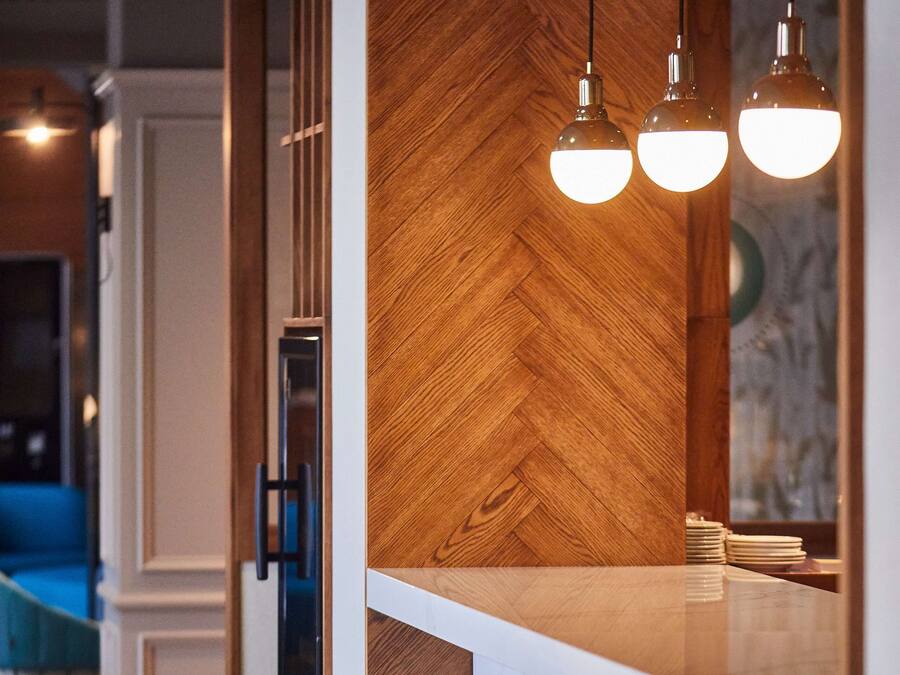 A bar area with wooden accents, hanging pendant lights, and bar stools.
