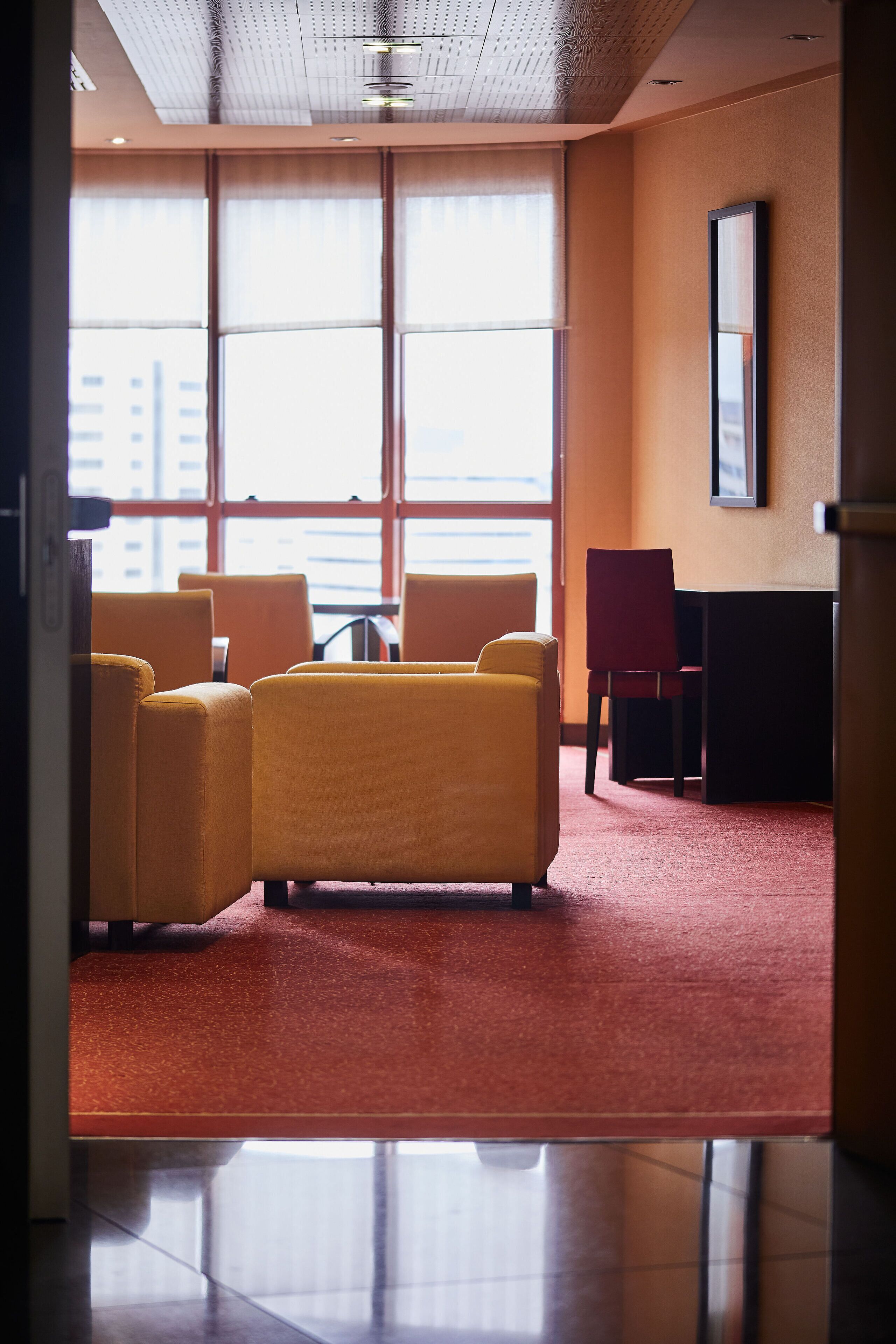 A hotel lobby with a seating area, a table, and a large window with a view of buildings.