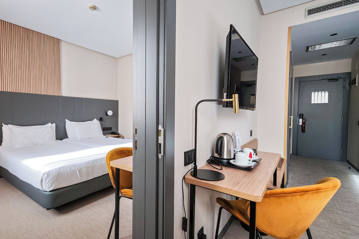 Ein Hotelzimmer mit einem Bett, einem Schreibtisch mit Stuhl, einem Fernseher und einer Kaffeemaschine.