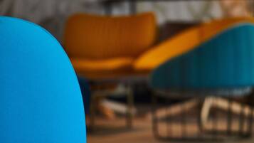 Een moderne woonkamer met een blauwe bank, een gele fauteuil en een blauwe stoel.