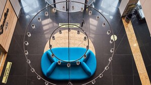 A circular seating area with blue chairs, a central table, and a glass ceiling allowing natural light.
