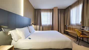 Een hotelkamer met een groot bed, een bureau, een stoel en een lamp.