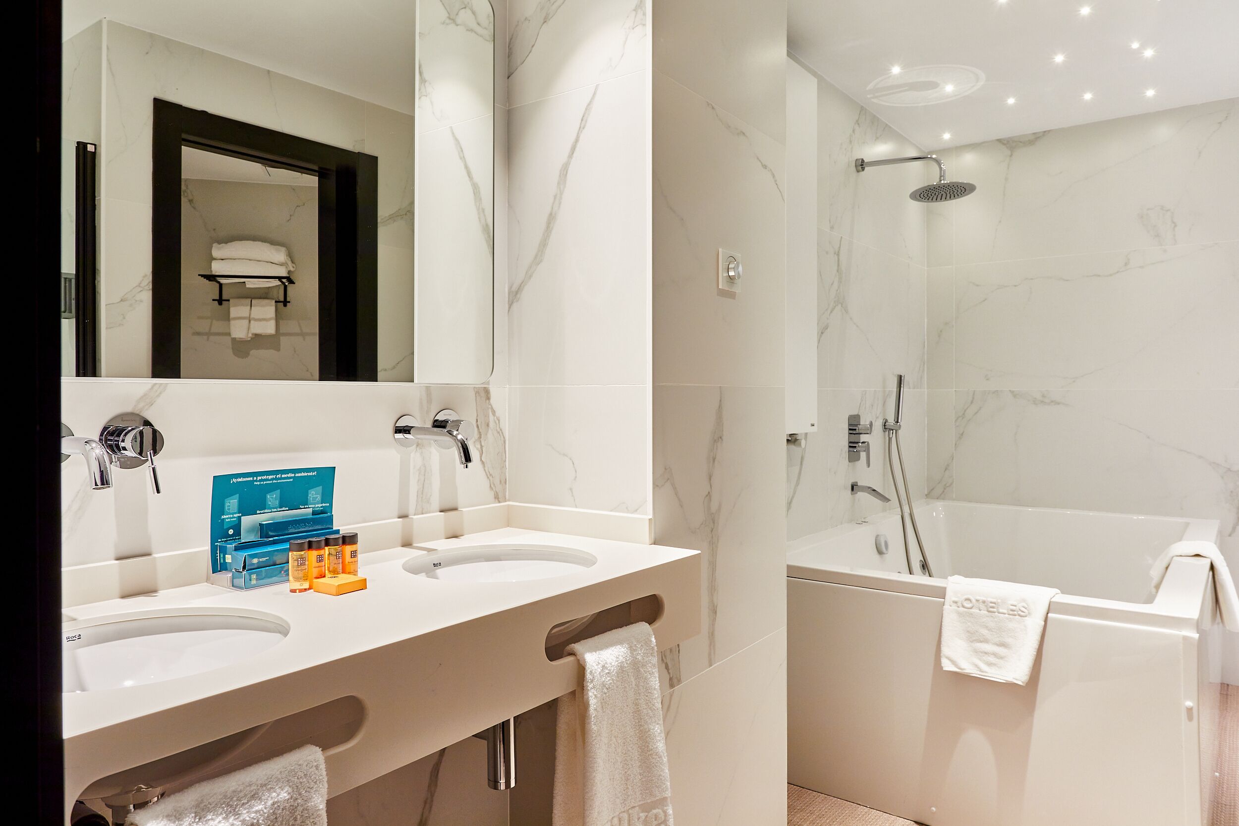 Un baño moderno con dos lavamanos, un espejo grande, una ducha y un perchero para toallas.