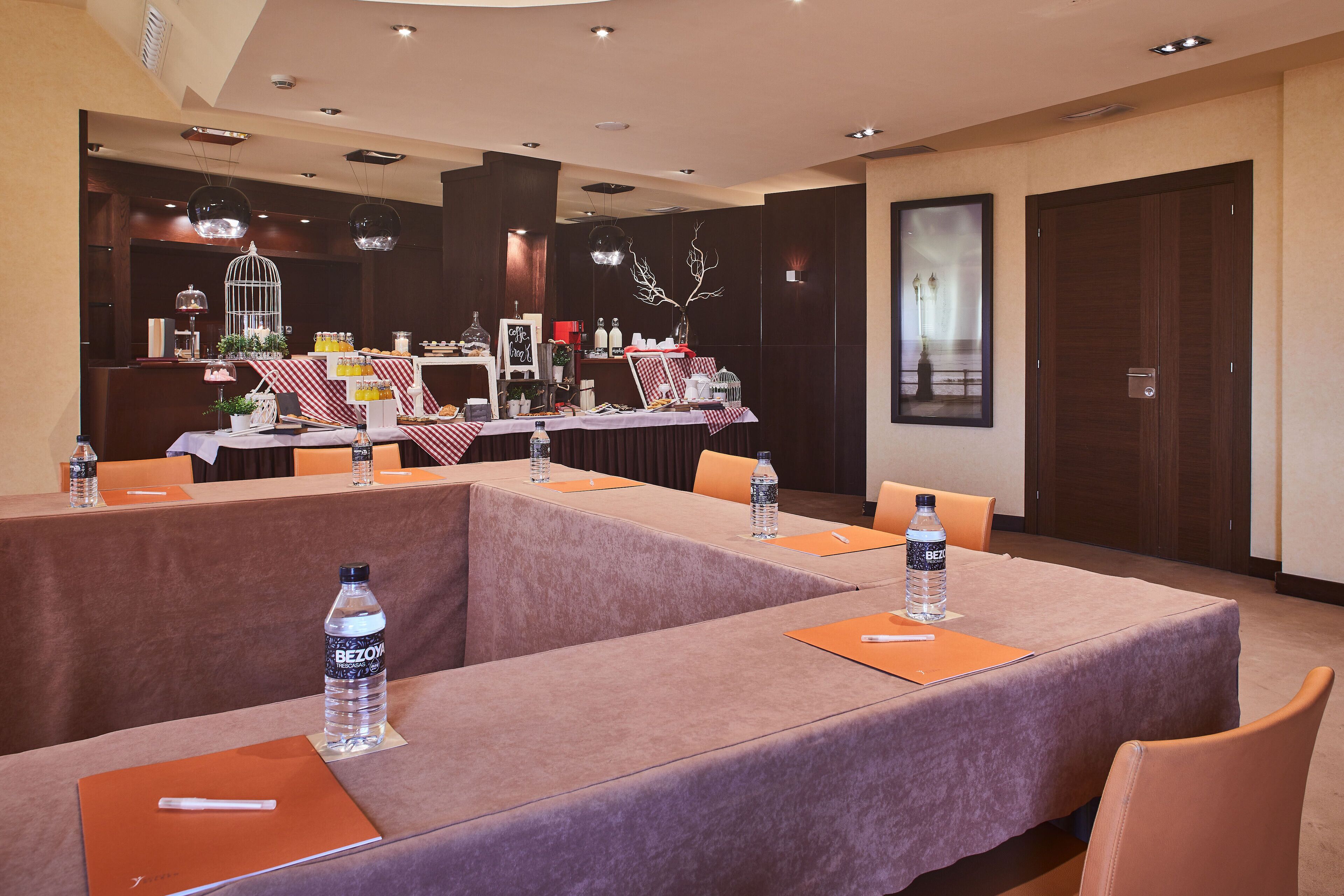 A conference room with long tables, water bottles, and orange folders.