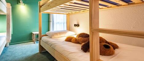 Ein Schlafzimmer mit Etagenbetten, einer grünen Wand, einem kleinen Tisch und einem Fenster.