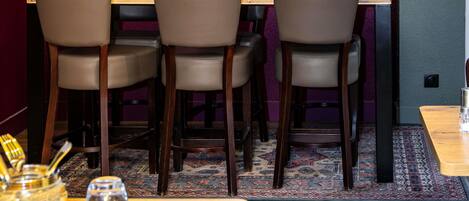 Interior de restaurante con una mesa de madera, cuatro sillas, piso alfombrado y una pared morada.