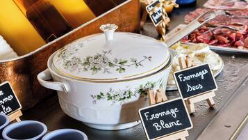 Un buffet con diversi cibi e bevande, tra cui una pentola grande di zuppa, formaggio e carne.