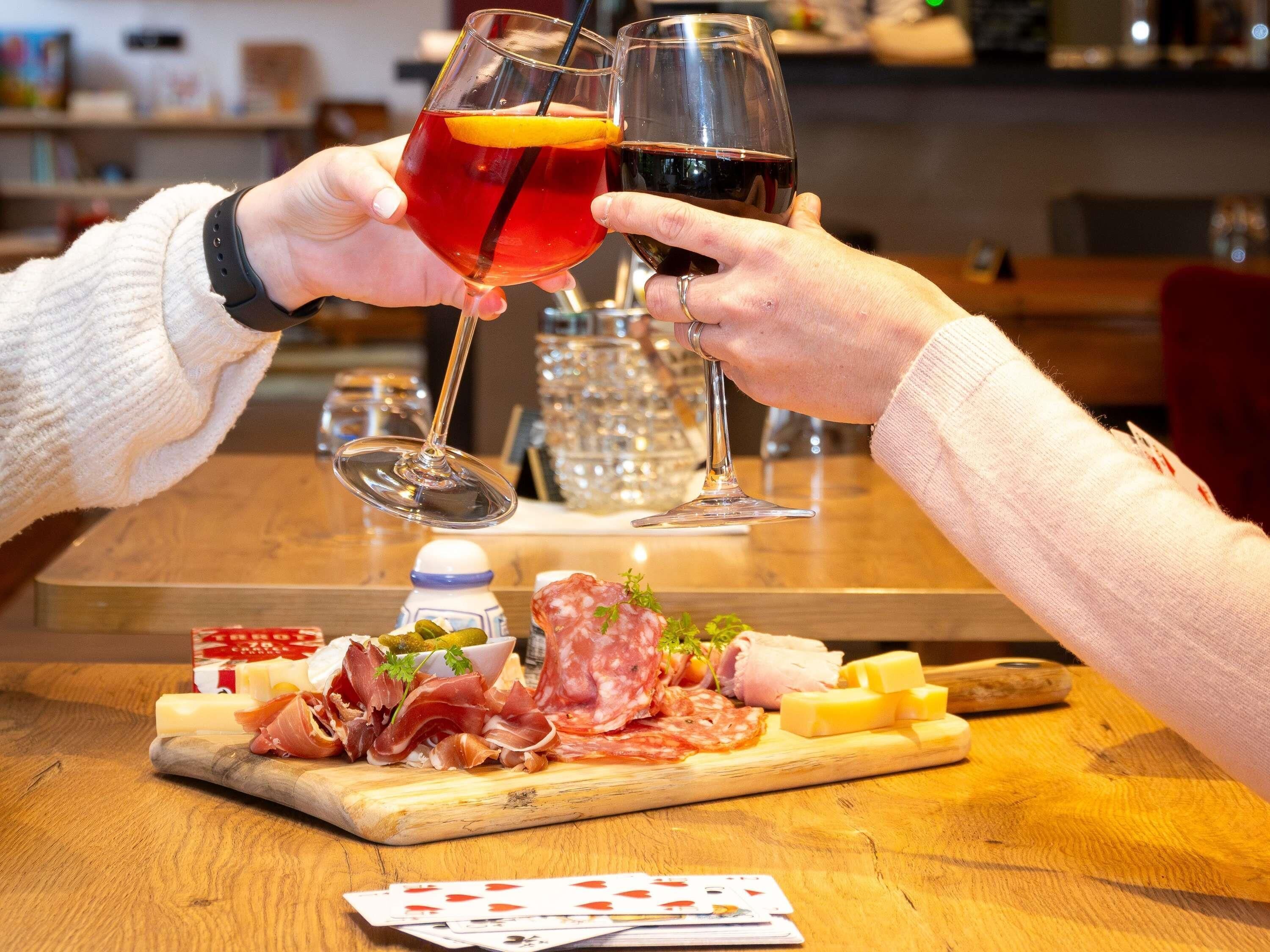 Una mesa de madera con varios quesos, embutidos y una botella de agua.