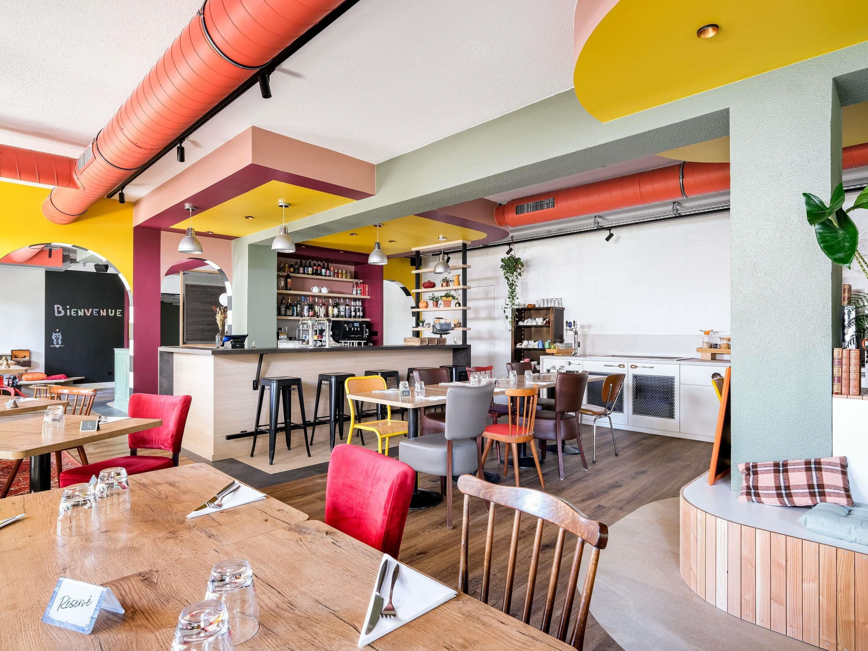 Een restaurantinterieur met een bar, verschillende zithoeken en een zichtbaar 'Bienvenue' bord.