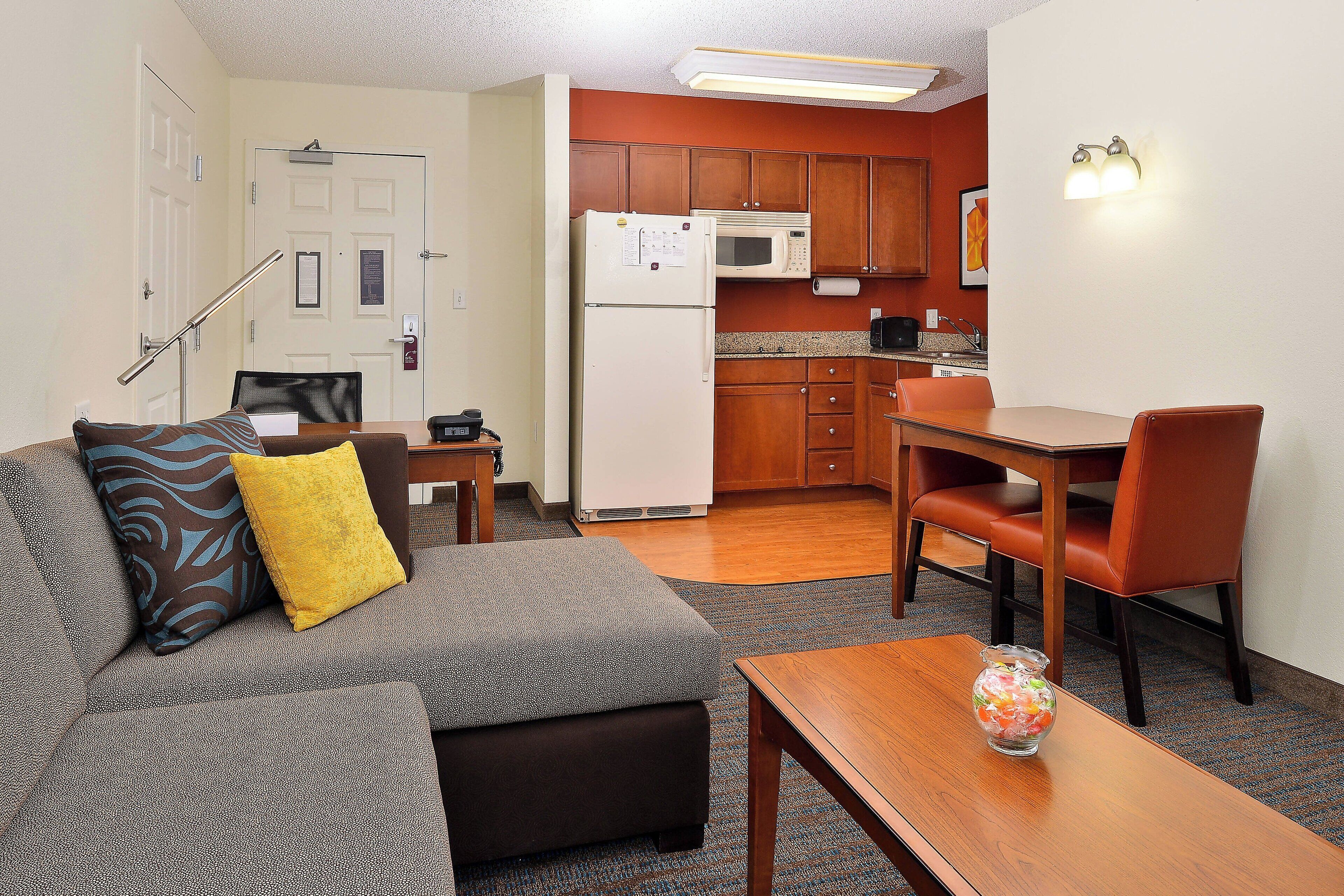 A compact living space with a kitchenette, a dining area, and a seating area with a sofa and ottoman.