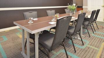 Une salle de conférence avec une longue table, six chaises et une petite plante.