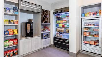 A coffee station with a coffee machine and a refrigerated display of beverages.