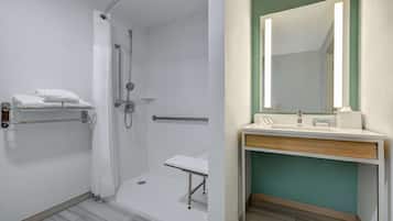 Un baño con ducha, lavamanos y espejo.