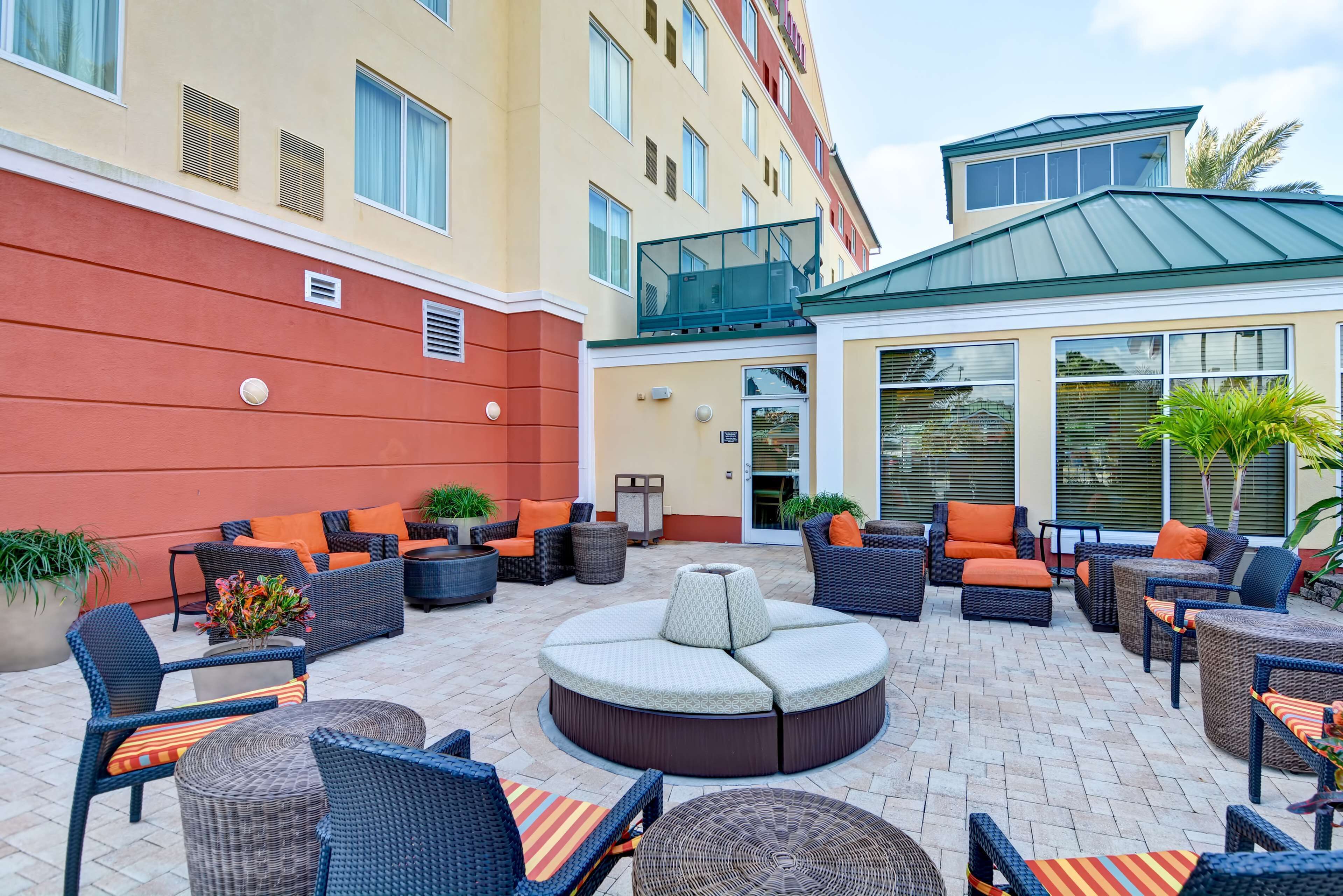 A hotel patio with outdoor seating, including sofas and chairs, and a central round table.