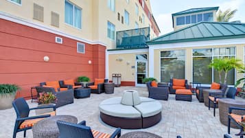 A hotel patio with outdoor seating, including sofas and chairs, and a central round table.
