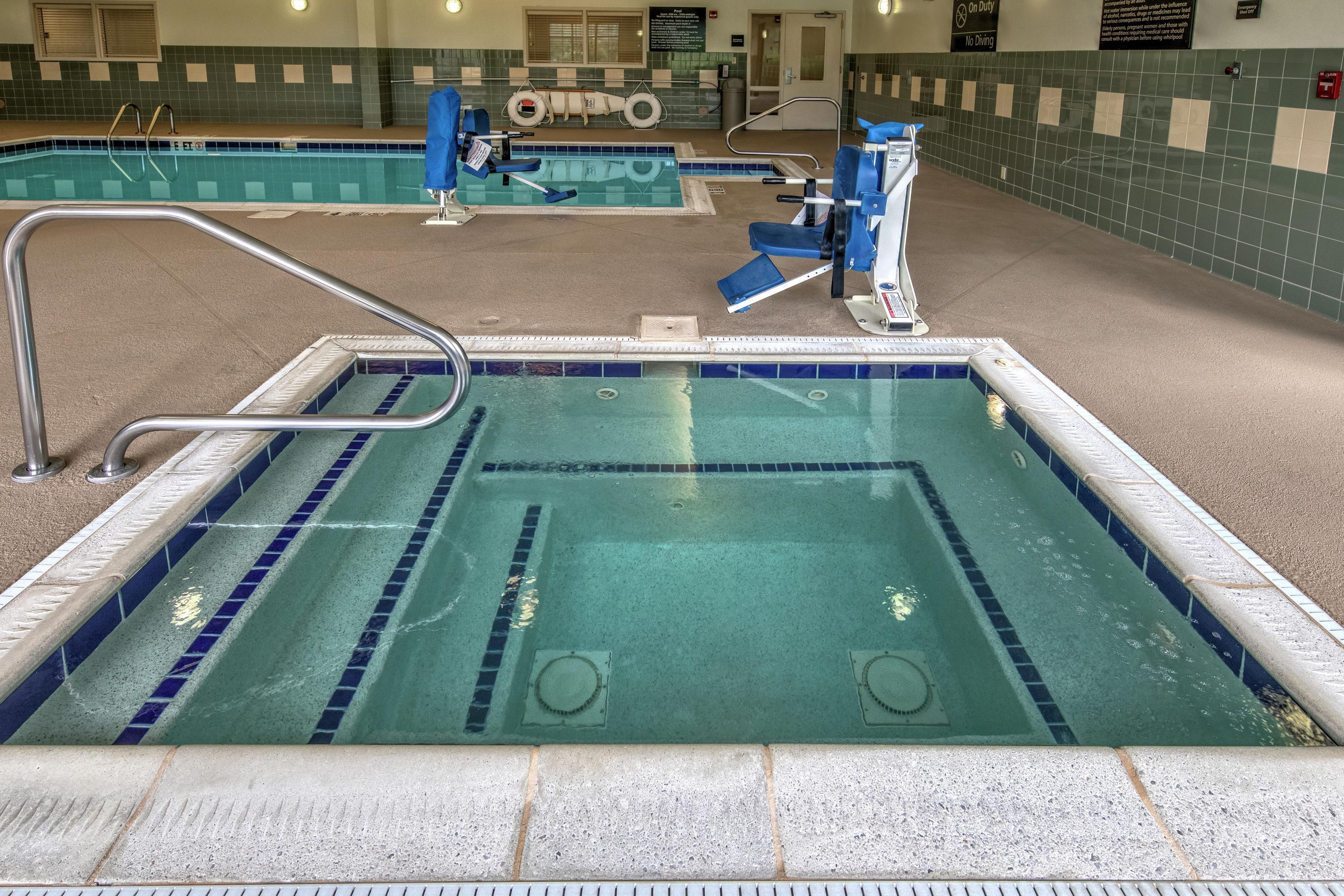 An indoor swimming pool with a lifeguard chair, a pool ladder, and a starting block.