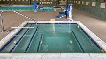 An indoor swimming pool with a lifeguard chair, a pool ladder, and a starting block.