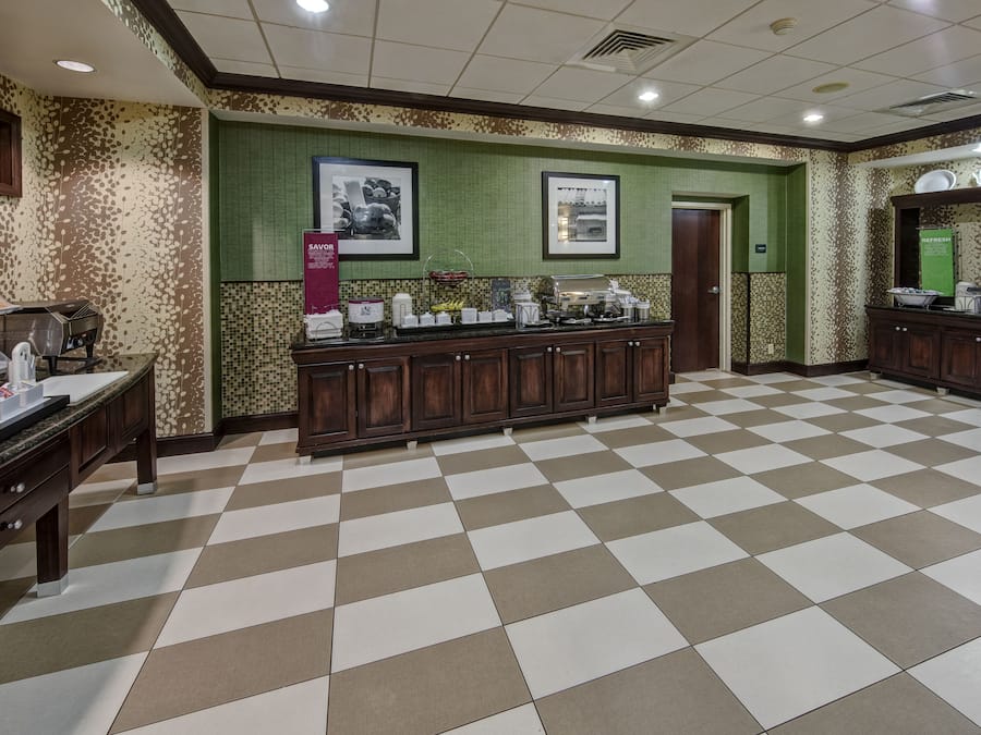 A hotel lobby with a checkered floor, a buffet area, and framed pictures on the wall.