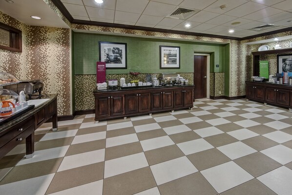 Un vestíbulo de hotel con piso a cuadros, una zona de buffet y cuadros en la pared.