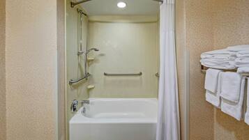 Ein Badezimmer mit Badewanne, Dusche und Handläufen.