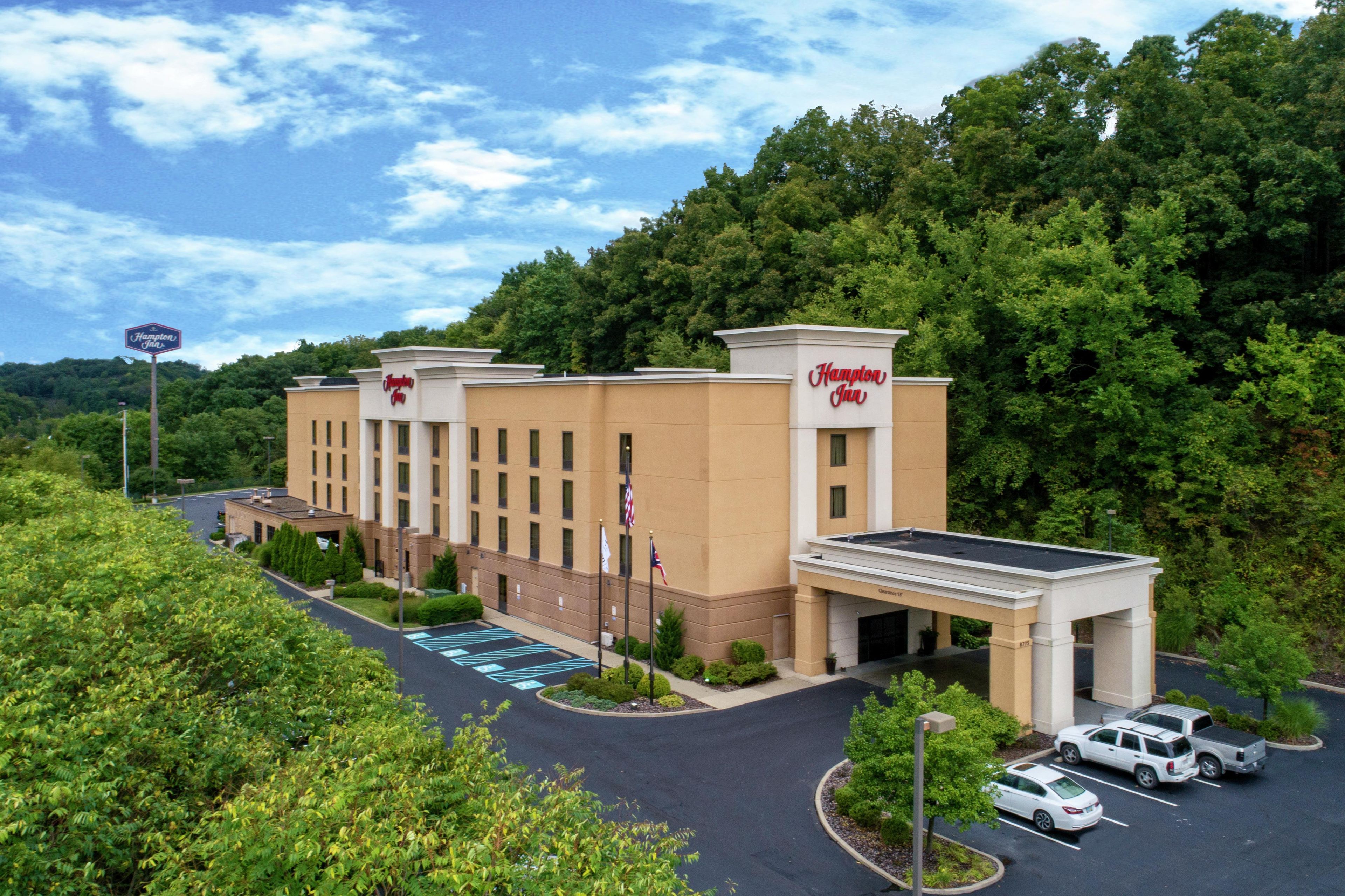 Un hotel Hampton Inn con estacionamiento y vistas del bosque circundante.
