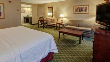 A hotel room with a bed, a sofa, a desk, a television, and a bathroom.