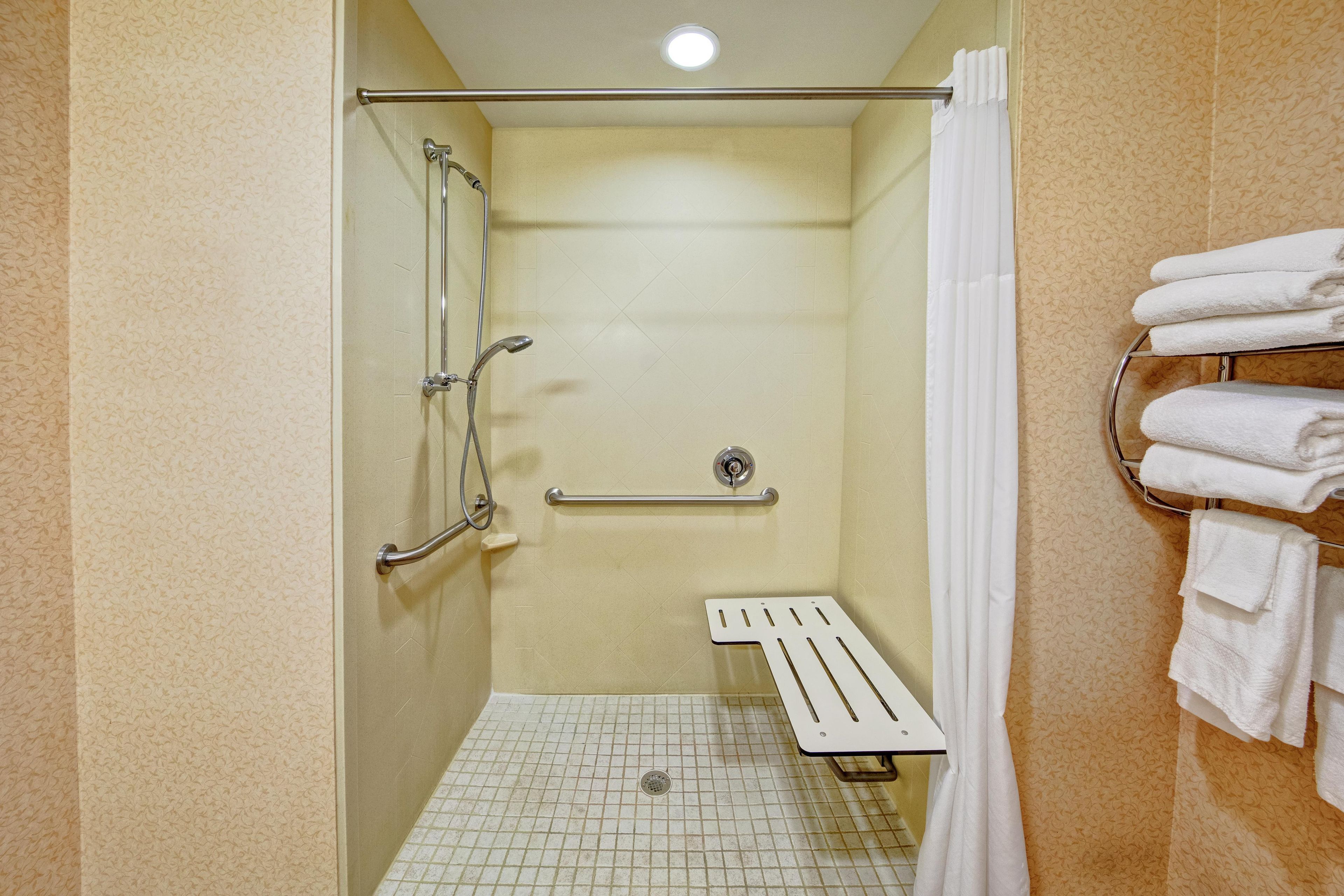 A shower stall with a grab bar, a towel rack, and a showerhead.