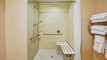 A shower stall with a grab bar, a towel rack, and a showerhead.