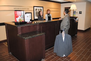 A reception desk with a 'Welcome to Cambridge' sign, a framed picture, and a 'Manager On Duty' sign. - Hampton Inn Cambridge (Cambridge)