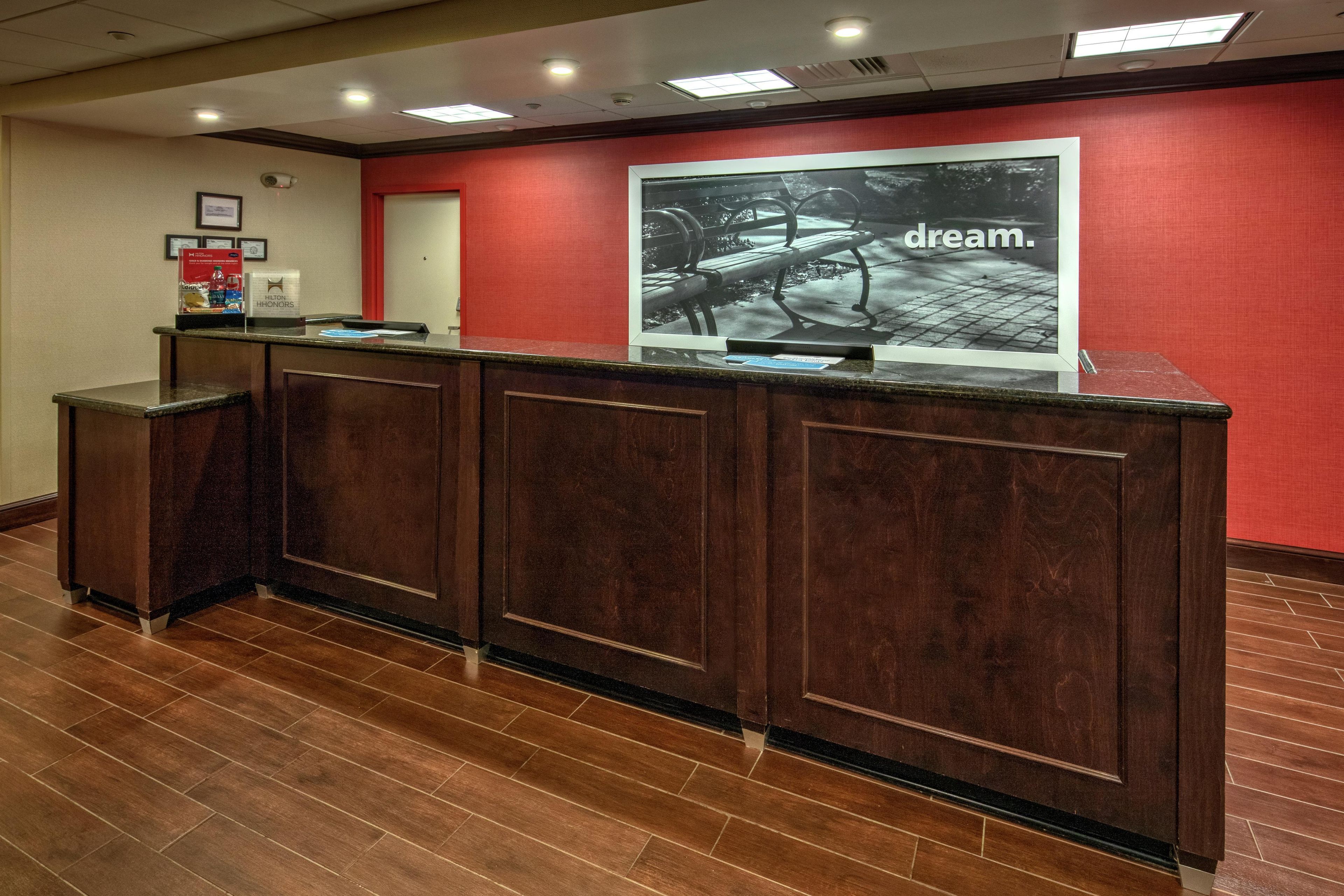 A reception desk with a red wall and a framed picture above it.
