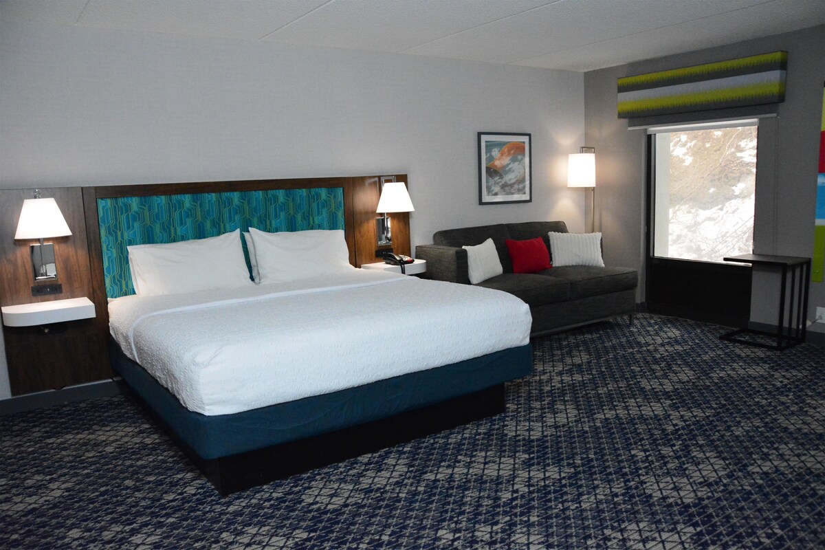 Una habitación de hotel con una cama grande, un sofá, un escritorio y una ventana.