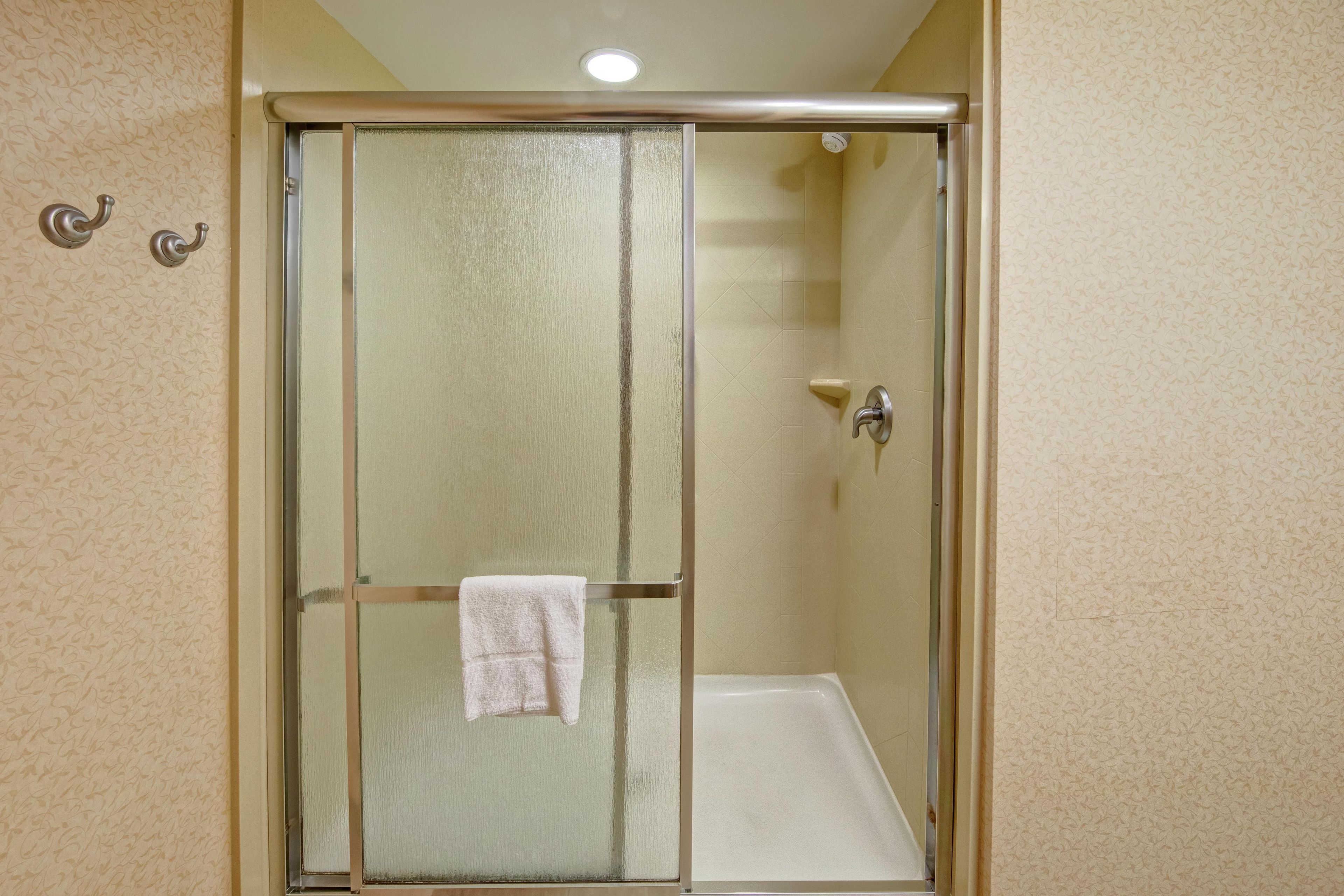 Une cabine de douche fermée par des parois de verre, avec une serviette blanche accrochée à la poignée de la porte.