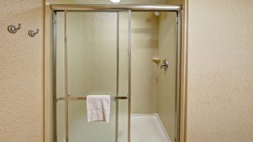 Une cabine de douche fermée par des parois de verre, avec une serviette blanche accrochée à la poignée de la porte.