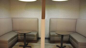 A corner seating area with two cushioned benches and a small round table, each with a lamp above.