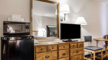 Une chambre d’hôtel équipée d’une commode en bois, d’un four à micro-ondes, d’une télévision, d’une lampe et d’une chaise.