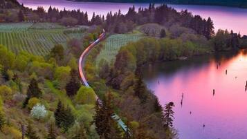 A scenic view of a lake surrounded by forested hills and a winding road.