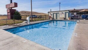 A swimming pool with a fence, a sign for Quality Inn & Suites, and a small building with a sign that says "No Diving".