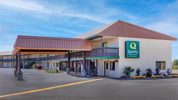 A Quality Inn & Suites by Choice Hotels with a covered outdoor seating area and a two-story building.