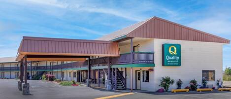 A Quality Inn & Suites by Choice Hotels with a covered outdoor seating area and a two-story building.