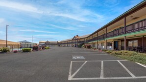 A hotel with a covered outdoor seating area and a parking lot.