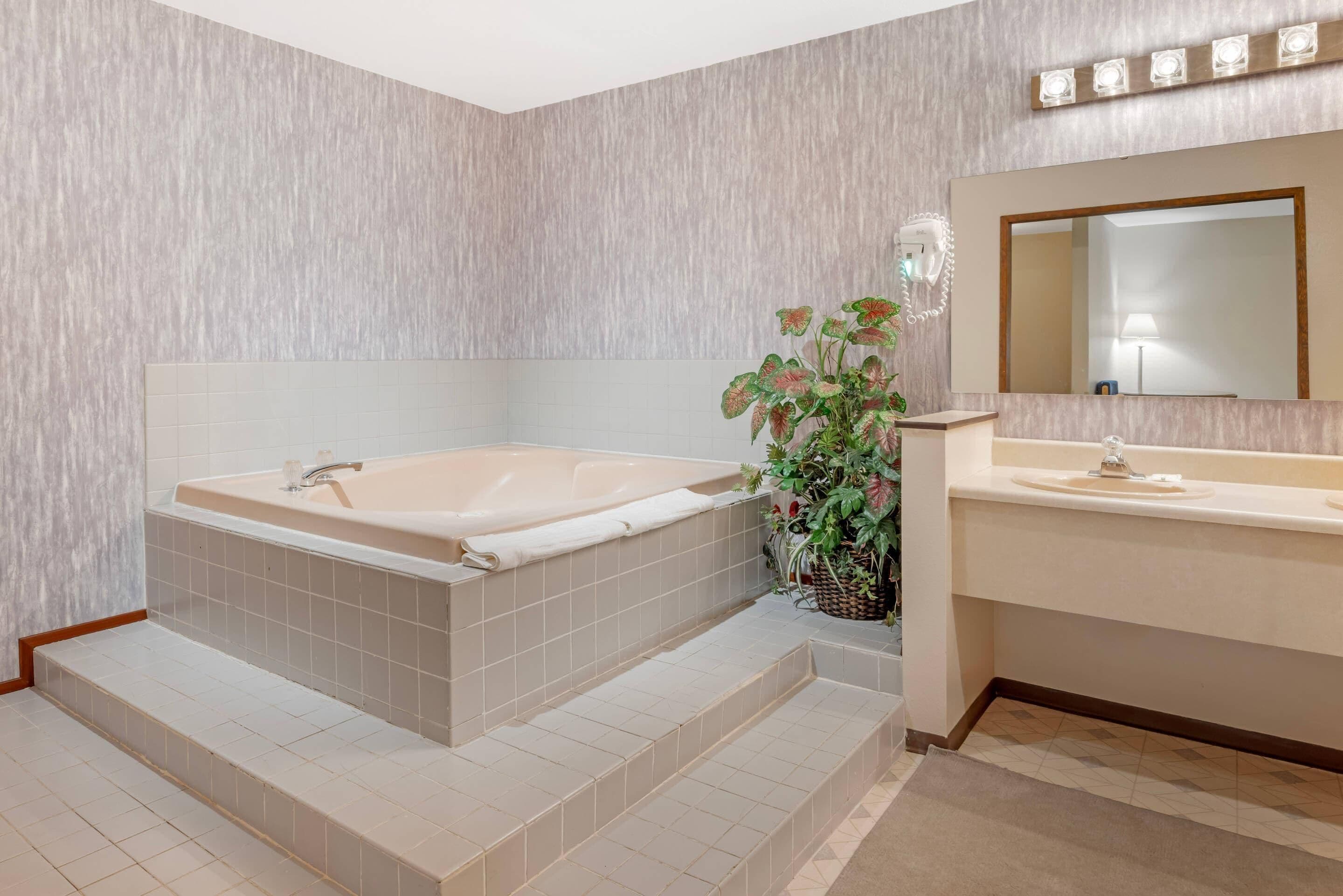 A modern bathroom with a freestanding bathtub, a vanity with a mirror, and a potted plant.