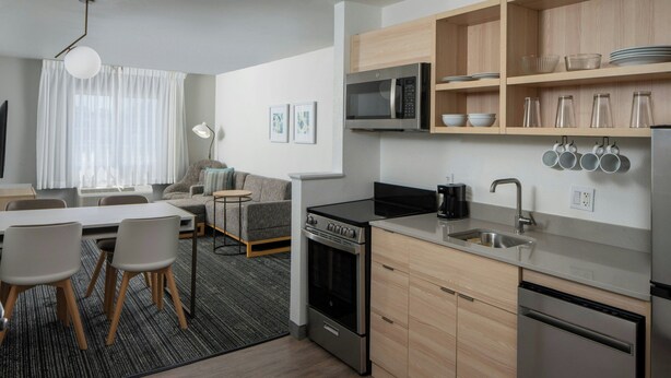 A modern kitchen with stainless steel appliances, wooden cabinets, and a dining area with a table and chairs.