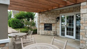 A covered patio with stone walls, a fireplace, and outdoor seating.
