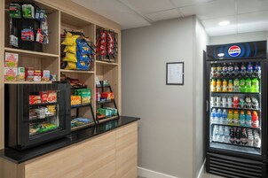Una máquina expendedora llena de diversas bebidas y un refrigerador con aperitivos y refrescos.