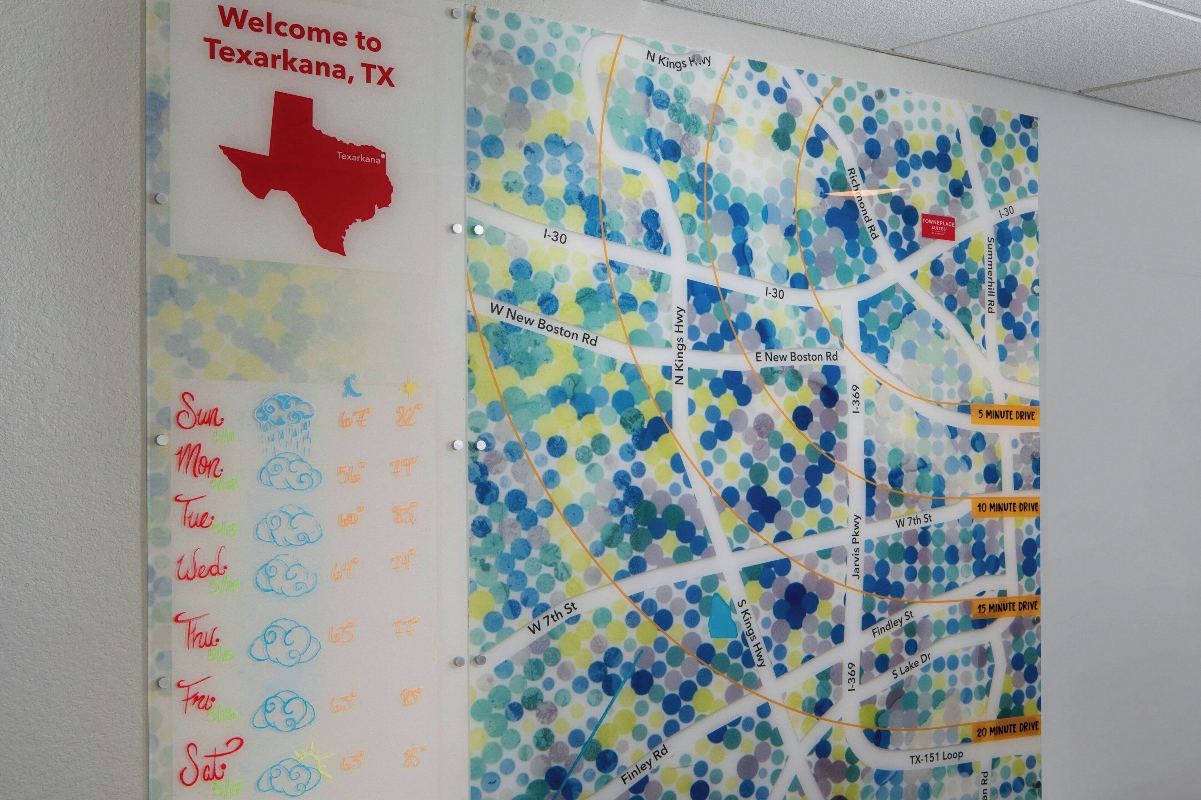 A wall with a map of Texarkana, TX, featuring a red Texas outline and a weather forecast section.