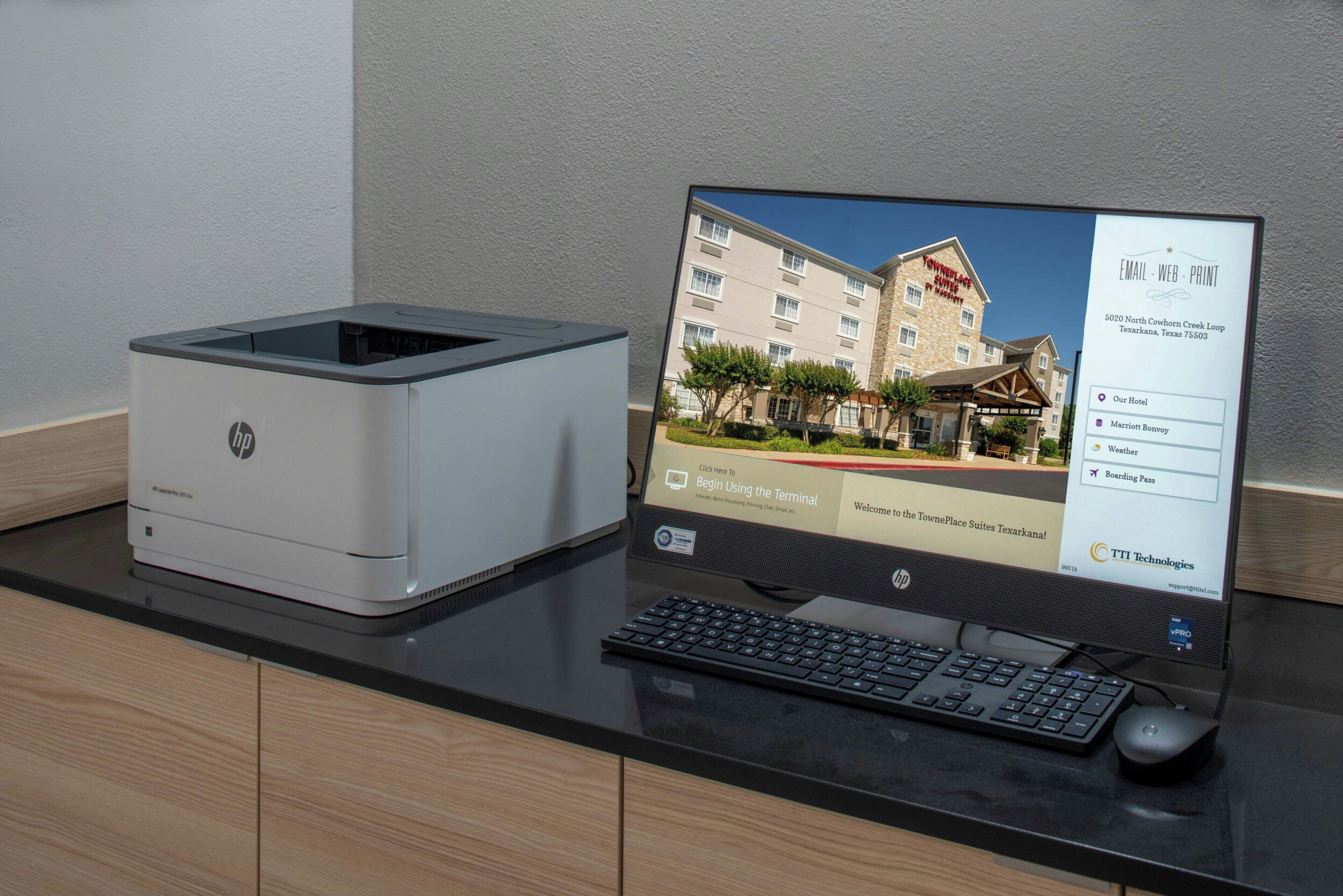 A desktop computer with a monitor displaying a hotel website, an HP LaserJet printer, and a keyboard on a desk.