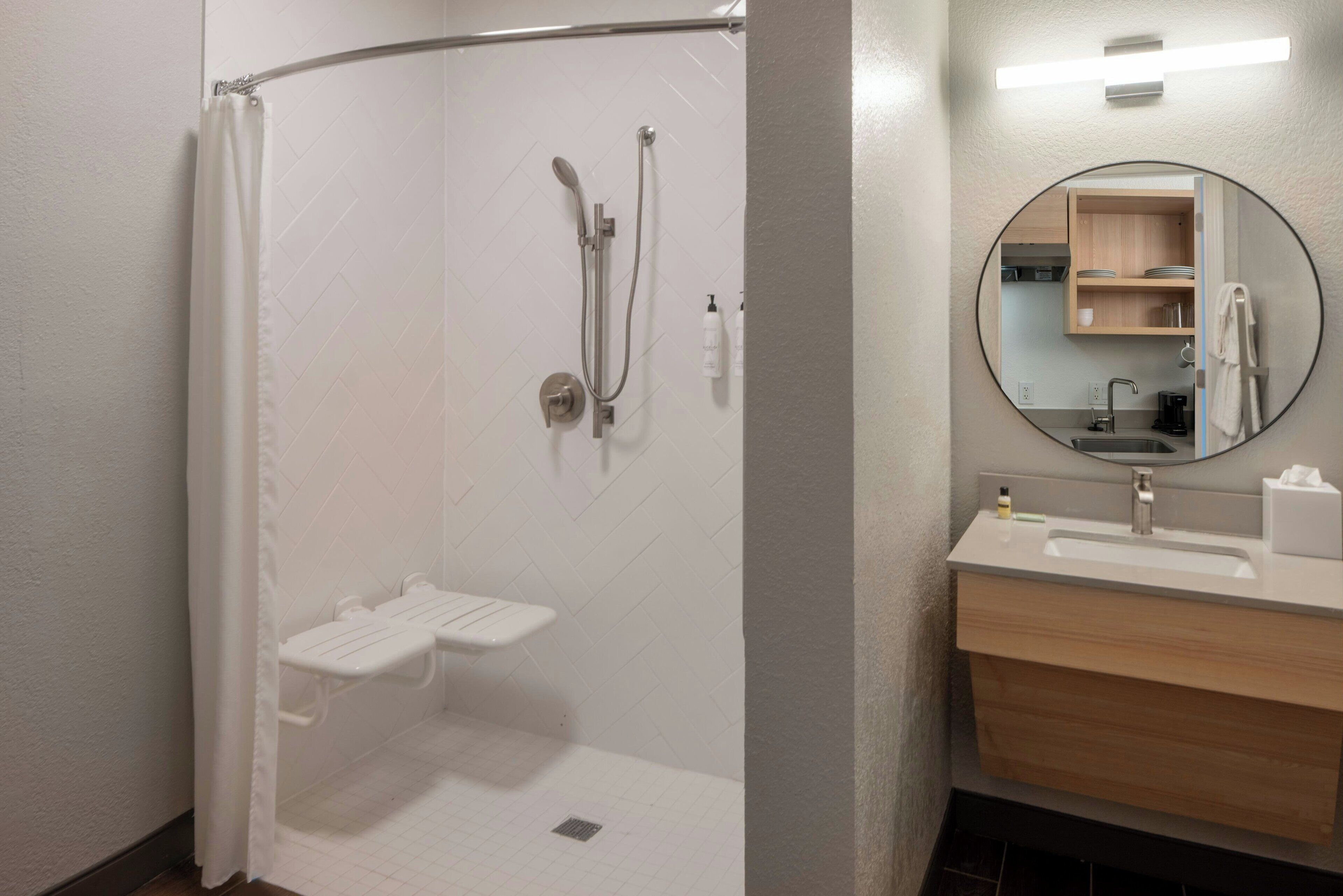 Un baño moderno con ducha, lavamanos y espejo.
