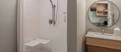 Un baño moderno con ducha, lavamanos y espejo.