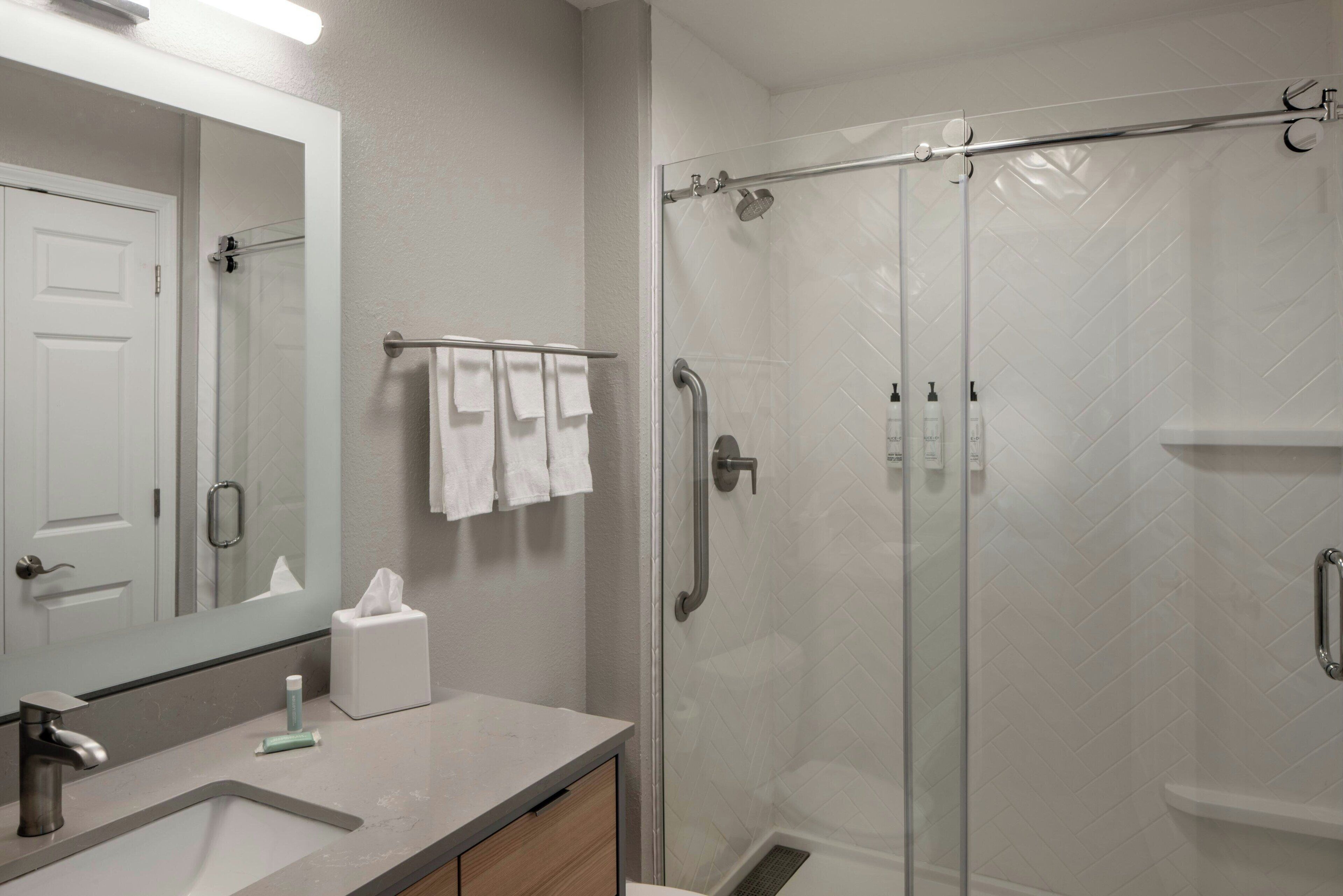 Une salle de bain moderne avec une douche à parois de verre, un lavabo avec un miroir et un porte-serviettes.
